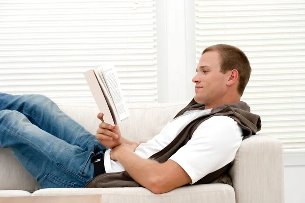 Aantrekkelijke man leesboek glimlachen — Stockfoto