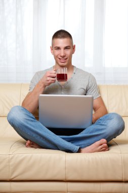 Young man sitting at home and watching his message clipart