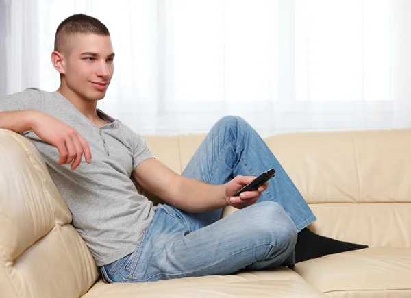 Young handsome man with remote control — Stock Photo, Image