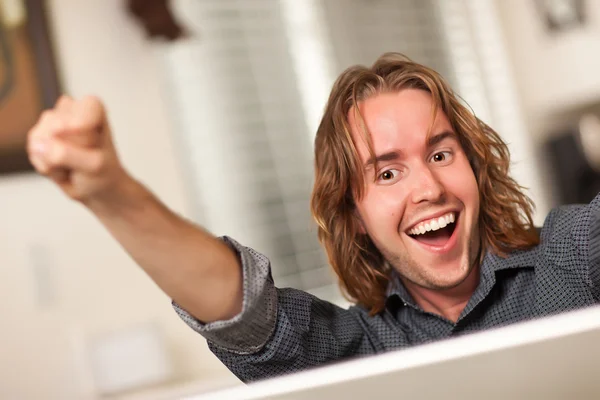 Podekscytowany młody człowiek przy użyciu komputera przenośnego — Zdjęcie stockowe