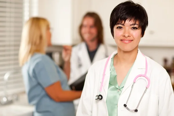 Hübsche Ärztin lächelt in die Kamera, während Kollegen reden — Stockfoto