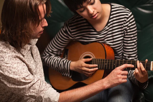Joven músico enseña a estudiante femenina a tocar la guitarra — Foto de Stock