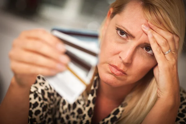 Расстроенная женщина, вопиющая на свои многочисленные кредитные карты — стоковое фото