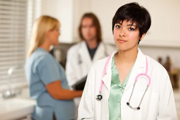 Pretty Latino Doctor Smiles at Camera as Colleagues Talk — Stock Photo, Image