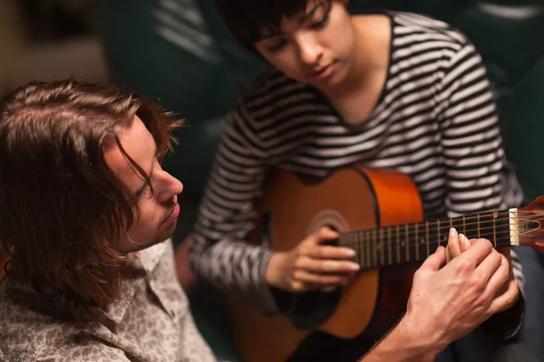 Un jeune musicien apprend à une étudiante à jouer de la guitare — Photo