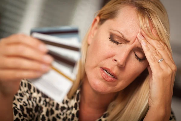Mulher perturbada segurando seus muitos cartões de crédito — Fotografia de Stock