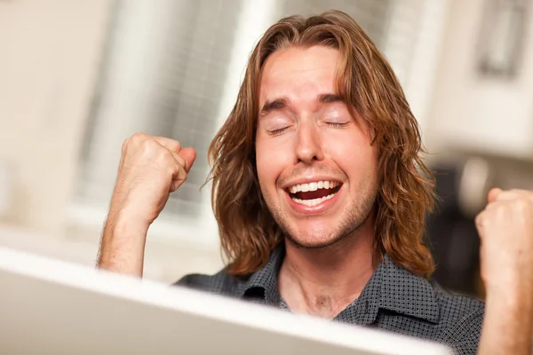 Torcendo jovem homem usando computador portátil — Fotografia de Stock
