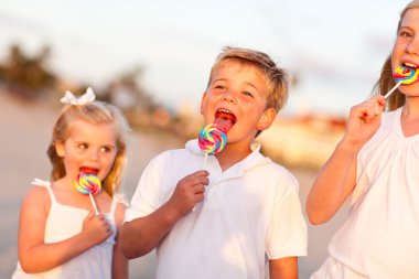 Cute Brother and Sisters Enjoying Their Lollipops Outside clipart