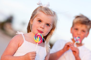 Cute Little Girl and Brother Enjoying Their Lollipops clipart