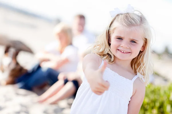 Schattige blonde meisje met duimen omhoog op het strand — Stockfoto