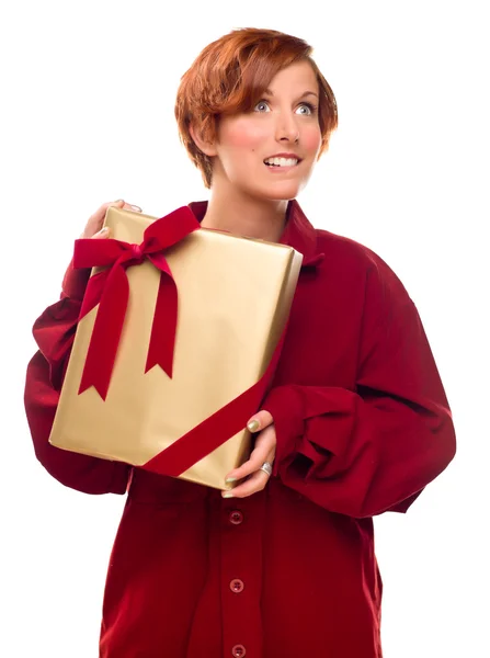 Прекрасная рыжеволосая девочка покусала губу, держа в руках обмотанный подарок — стоковое фото