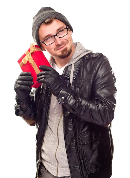 Vêtu chaudement jeune homme tenant cadeau enveloppé à son oreille — Photo