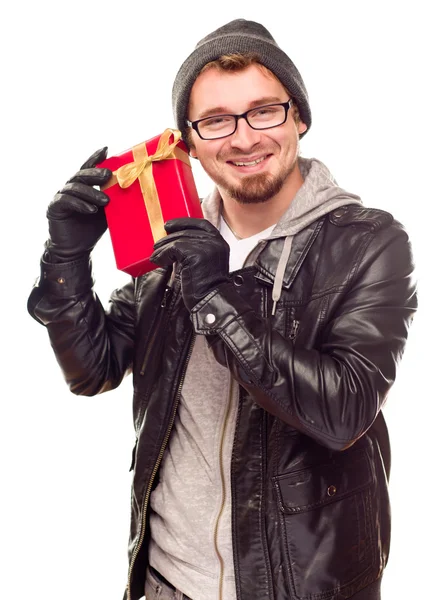 Vêtu chaudement jeune homme tenant cadeau enveloppé à son oreille — Photo
