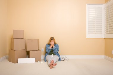 Upset Woman with Tissues on Floor Next to Boxes and Blank Sign in Empty Room. clipart