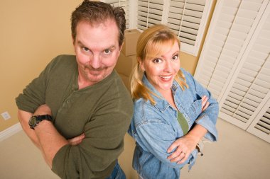 Smiling Goofy Couple and Moving Boxes in Empty Room. clipart