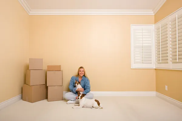 Mooie vrouw en honden met Verhuisdozen in kamer op verdieping — Stockfoto