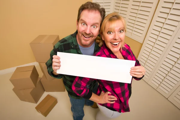 Happy Couple Holding Blank Sign in Room with Packed Boxes — Stock Photo, Image