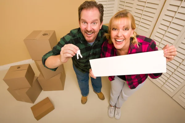 Goofy Couple Holding Keys Blank Sign Room Packed Cardboard Boxes — Stock Photo, Image