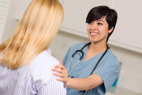 Привлекательная многонациональная молодая женщина-врач беседует с пациенткой — стоковое фото