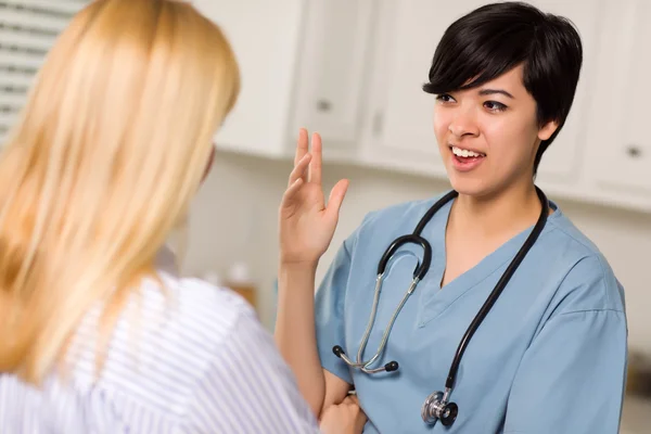 Çekici karışık ırk genç bir kadın doktor hasta ile konuşmak — Stok fotoğraf