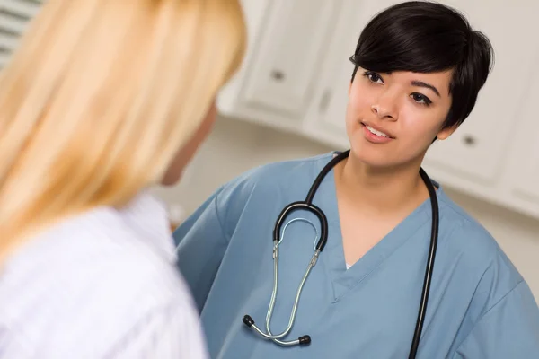 Atractiva raza mixta joven doctora hablando con paciente —  Fotos de Stock