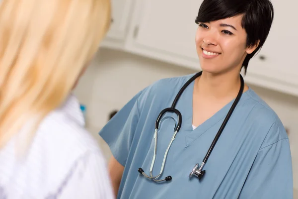 Atractiva raza mixta joven doctora hablando con paciente —  Fotos de Stock