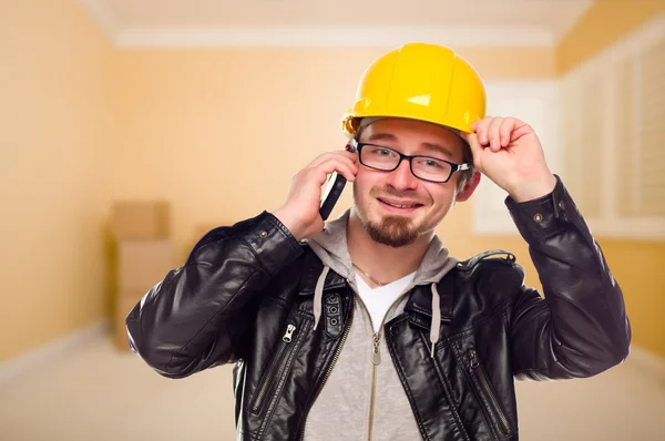 Fiatal vállalkozó kemény kalap viselése a sejt telefont a házban — Stock Fotó