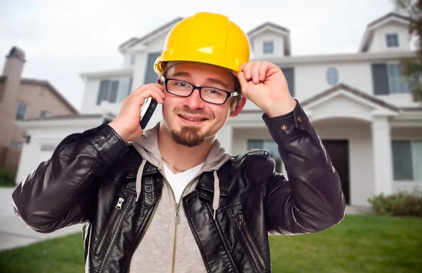 Подрядчик носит жесткую шляпу на телефоне перед домом — стоковое фото
