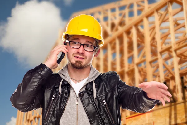 Jeune travailleur de la construction sur téléphone cellulaire devant la maison — Photo