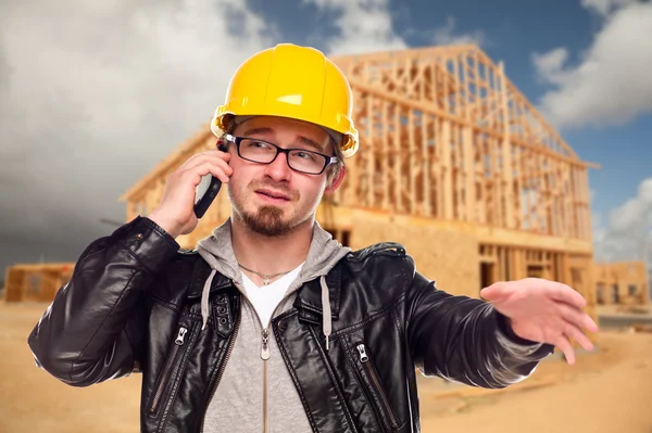 Trabajador joven de la construcción en el teléfono celular en frente de la casa — Foto de Stock
