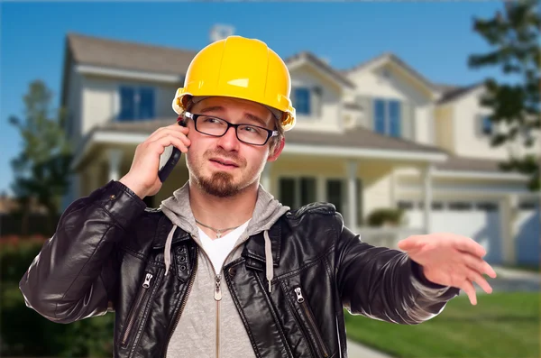 建築業者は家の前に電話でハード帽子をかぶっています。 — ストック写真