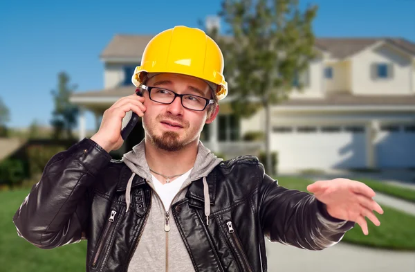 Підрядник носить жорсткий капелюх на телефоні перед будинком — стокове фото