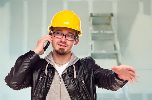 Entreprenör i hård hatt på mobiltelefon i Ofärdiga hus — Stockfoto