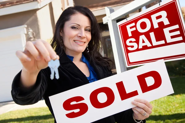 Hispanic Woman Holding Sold Real Estate Sign and Keys in Front H Royalty Free Stock Images