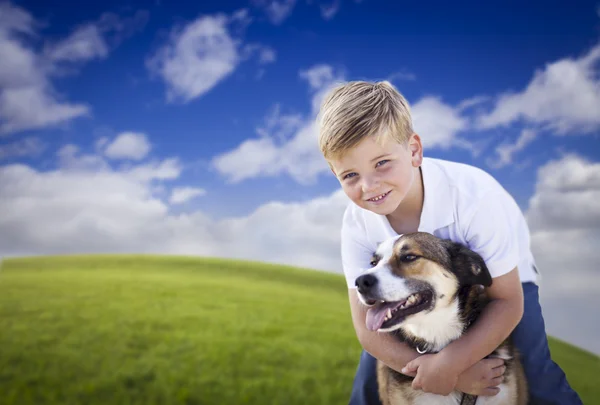 Stilig ung pojke leker med sin hund i gräset — Stockfoto