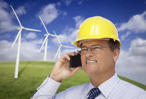 Helm dragen ingenieur op telefoon met turbines achter — Stockfoto