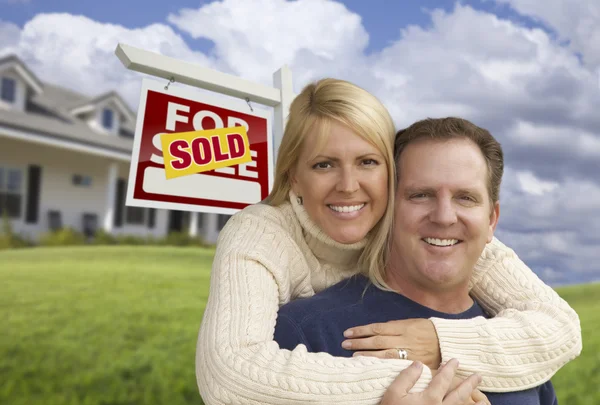 Pareja feliz abrazándose delante del letrero y la casa vendidos —  Fotos de Stock