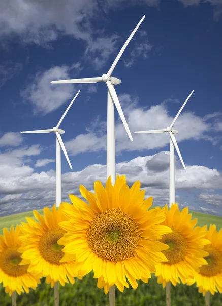 Ветряные турбины против драматического неба с яркими подсолнухами — стоковое фото