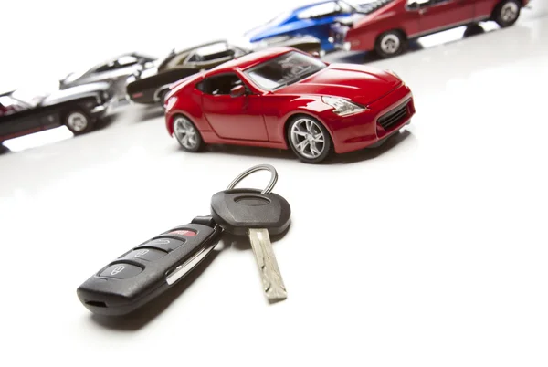 Autoschlüssel und mehrere Sportwagen auf weiß — Stockfoto