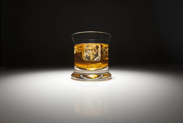Bicchiere di whisky e ghiaccio sotto la luce spot . — Foto Stock