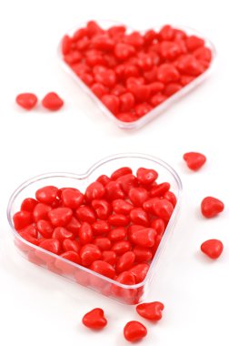Spicy, red hot cinnamon candy hearts in heart shaped dish in vertical format with selective focus clipart