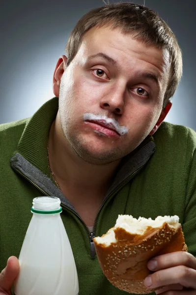 Retrato de un hombre divertido con pan y botella. Rastros de yogur en hi —  Fotos de Stock