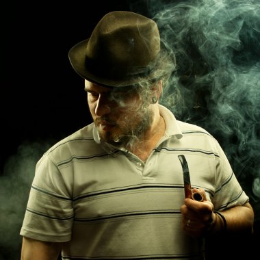 Dark fine art portrait of a smoking man in hat. With tobacco pip clipart