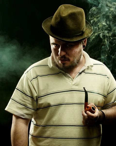 Dark fine art portrait of a smoking man in hat. With tobacco pip — Stock Photo, Image