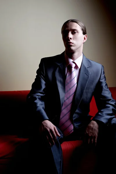 Kontrastowe portret przystojny poważny człowiek na kanapie — Zdjęcie stockowe