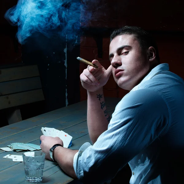 Dark fine art portrait of smoking young gambler — Stock Photo, Image