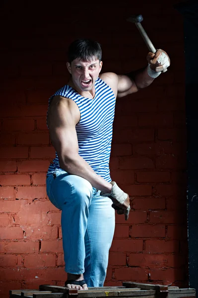 Angry muscular man with hammer in hand — Stock Photo, Image