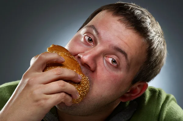 Homem corpulento faminto comendo pão branco — Fotografia de Stock