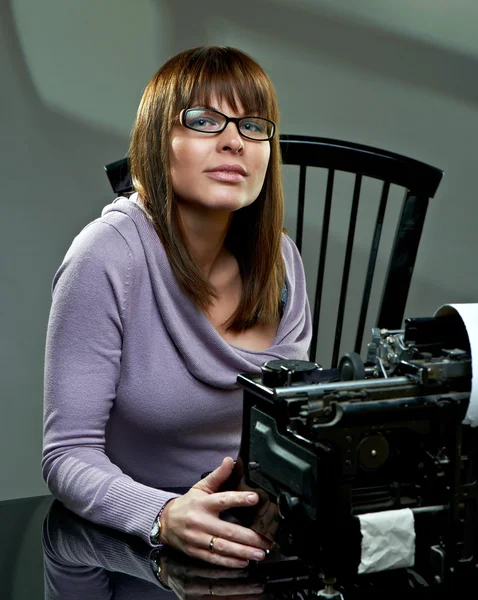 Piękna młoda kobieta w okularach na maszynie do pisania — Zdjęcie stockowe