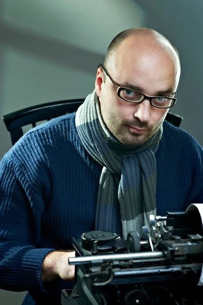 Altmodischer Glatzkopf mit Brille schreibt Buch auf einer alten Schreibmaschine Stockfoto